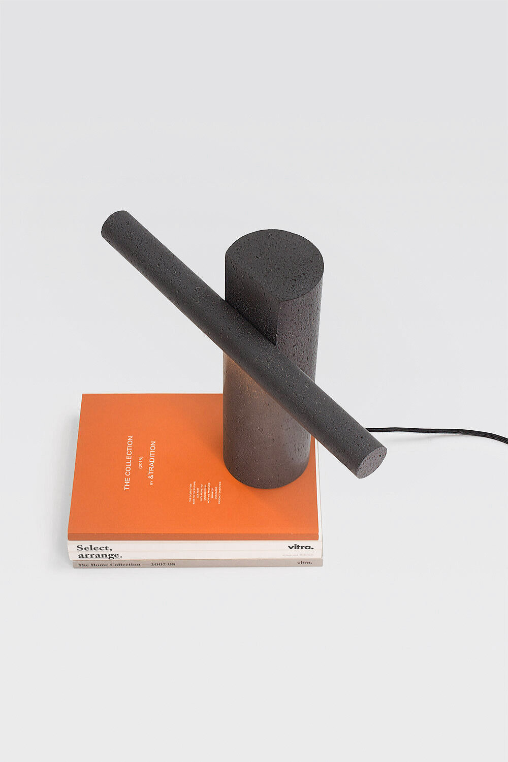 Drill Lamp by LeviSarha - Minimalist Table Lamp made of basalt, a volcanic stone standing on an orange book | Aesence