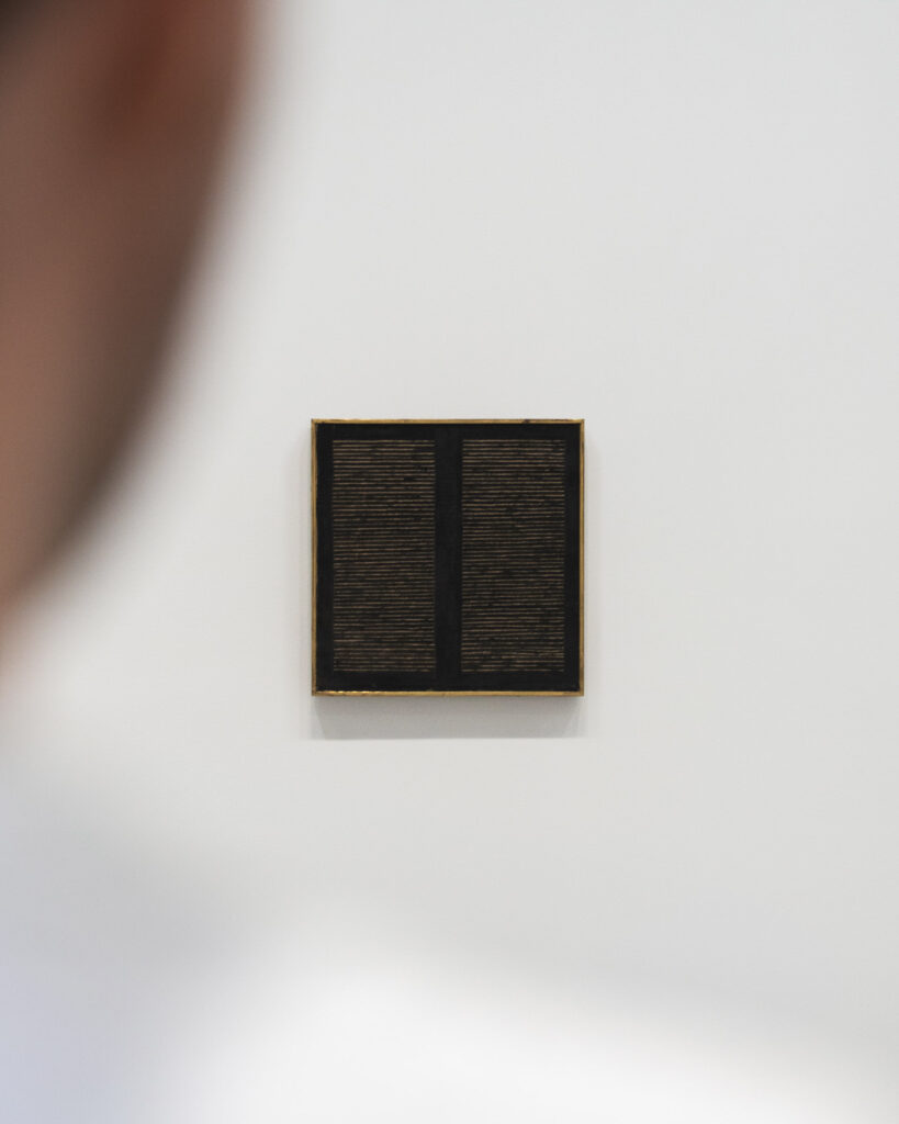 A man looking at an artwork by Agnes Martin, on view at 'Minimal' at Bourse de Commerce, Paris, 2025 © Photography by Aesence / Sarah Dorweiler